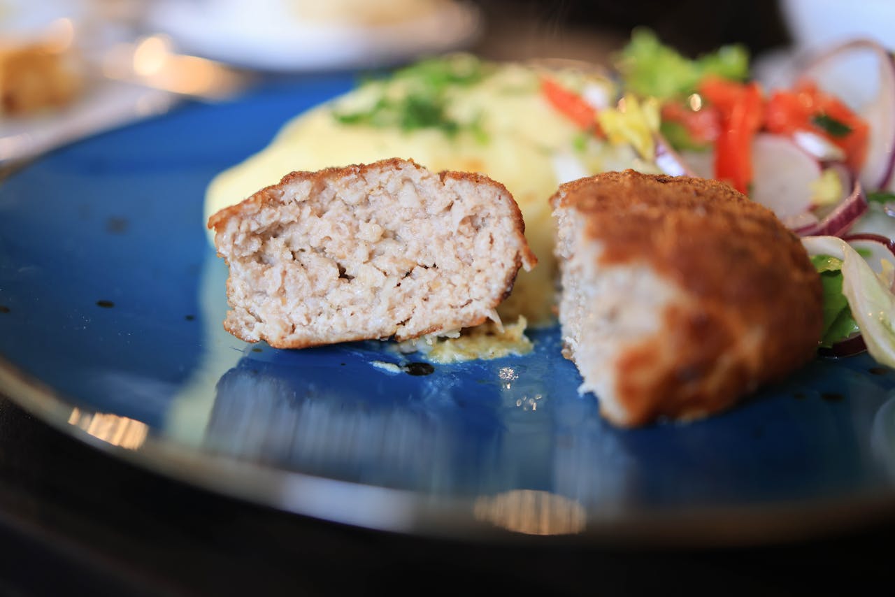 Close-up of a juicy chicken cutlet with a vibrant fresh salad on a blue plate.